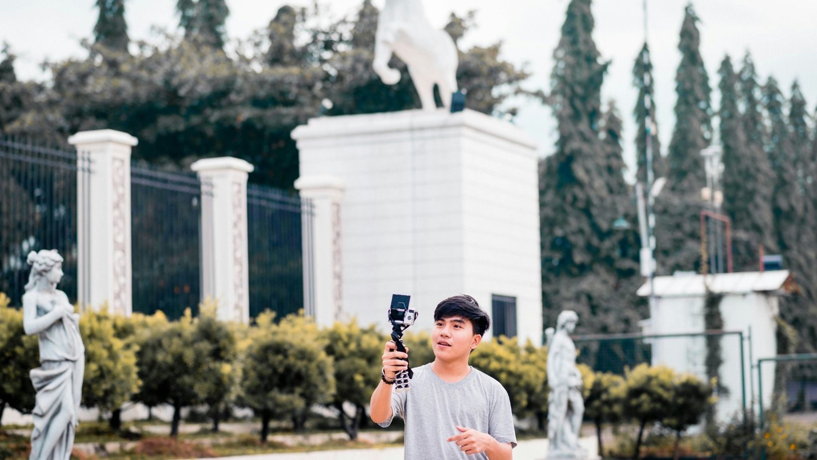 A traveler holding a small camera while recording a video outdoors