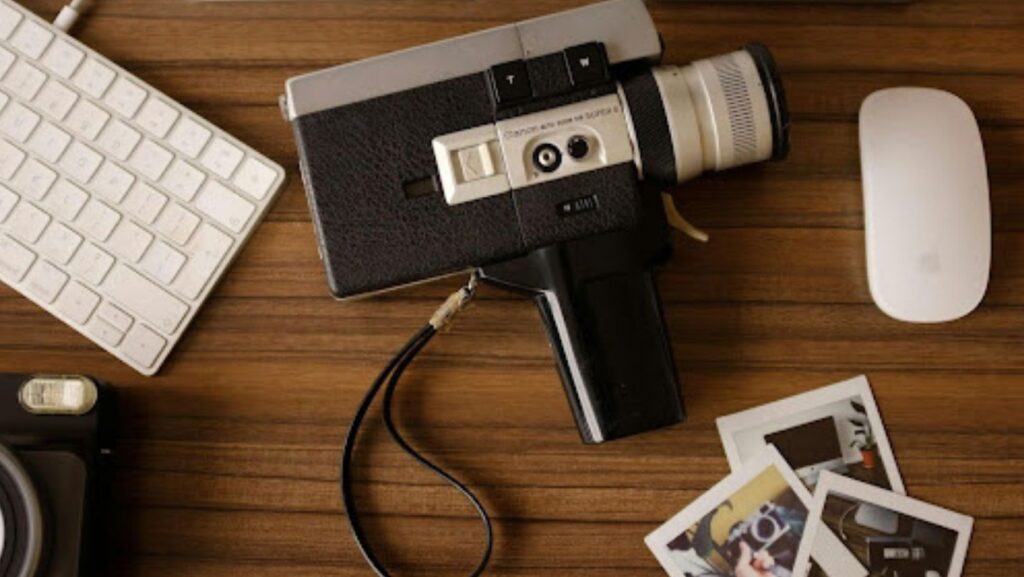 Vintage film camera and printed photos on a desk, symbolizing preserving old travel footage before it degrades