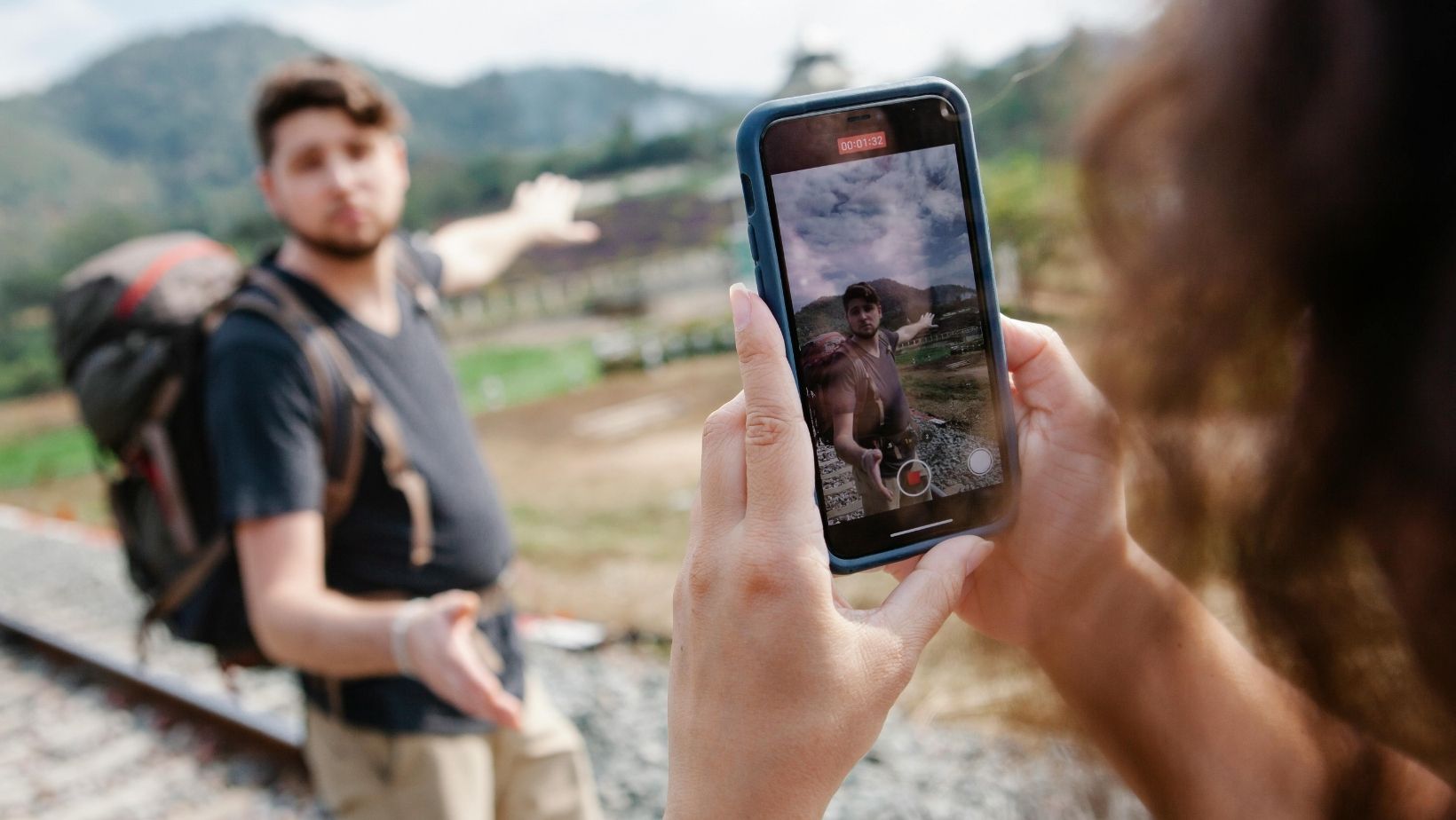 A person recording a travel companion on a smartphone during a trip